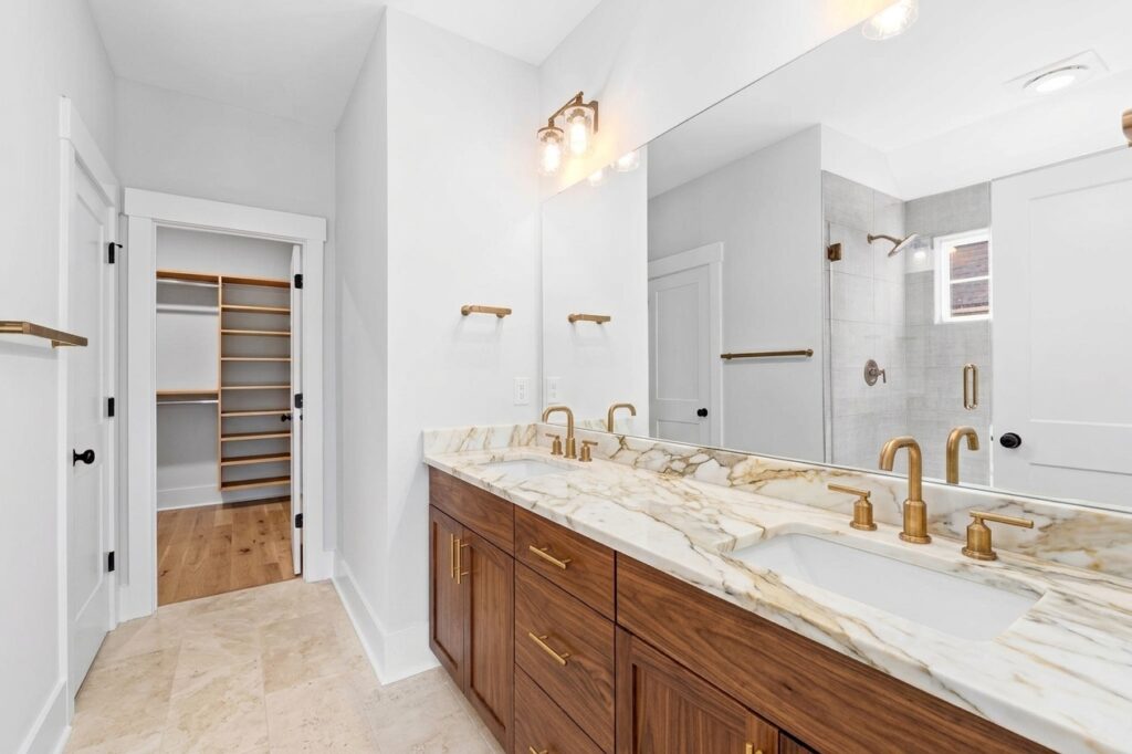 Walnut vanity with gold-veined countertop and brass fixtures